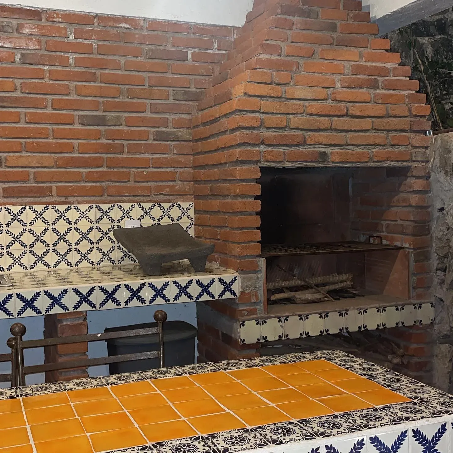 Asador de ladrillo con campana de obra, banca de talavera azul y blanca y barra de mosaico amarillo