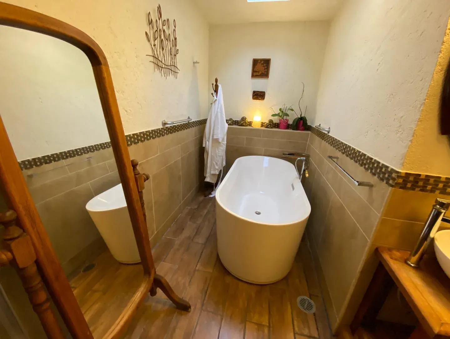 Baño de la Suite Principal con tina exenta, piso de madera, espejo de cuerpo entero y tragaluz