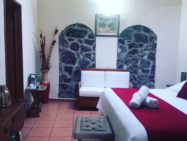 Rincón recogido de habitación con nichos de piedra volcánica, cómoda de madera y banca tapizada al pie de la cama